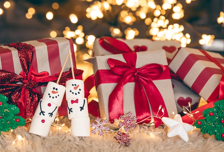 Christmas gift box on a background of Christmas tree, with marshmallow snowmen.