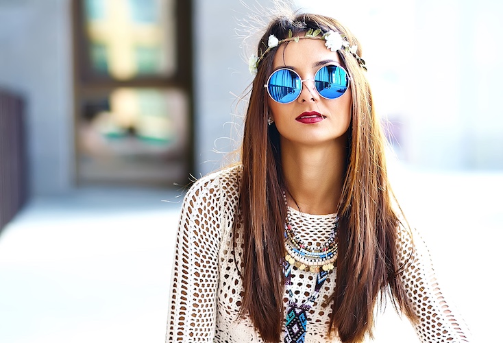 Funny stylish sexy smiling beautiful young hippie woman model in summer white hipster clothes posing in the street