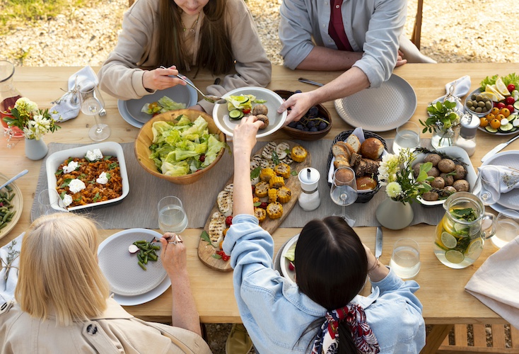 above view of table with delicious food and women sitting handing others plates.